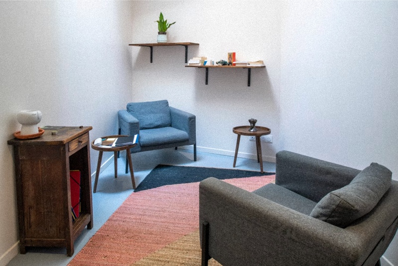 Espace de consultation épuré et minimaliste avec fauteuils confortables et étagères murales, dans un cabinet d’hypnose situé à Marseille.